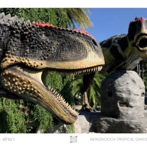 Two dinosaur statues in tropical garden.